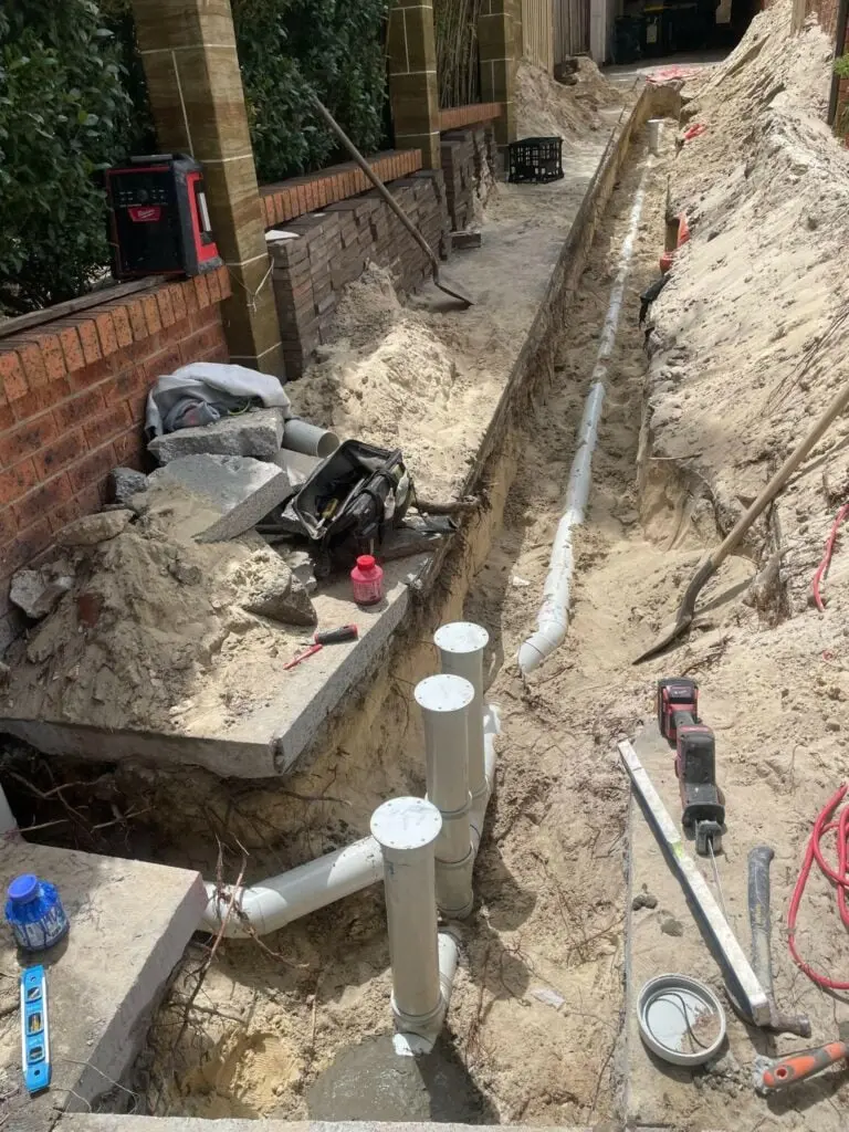 New PVC sewer line laid in a trench beside a house