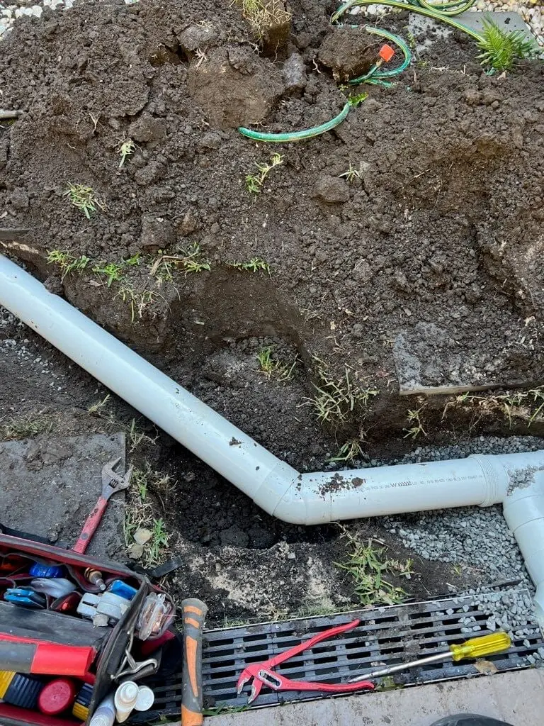 New stormwater pipe in a garden trench beside a pit grate
