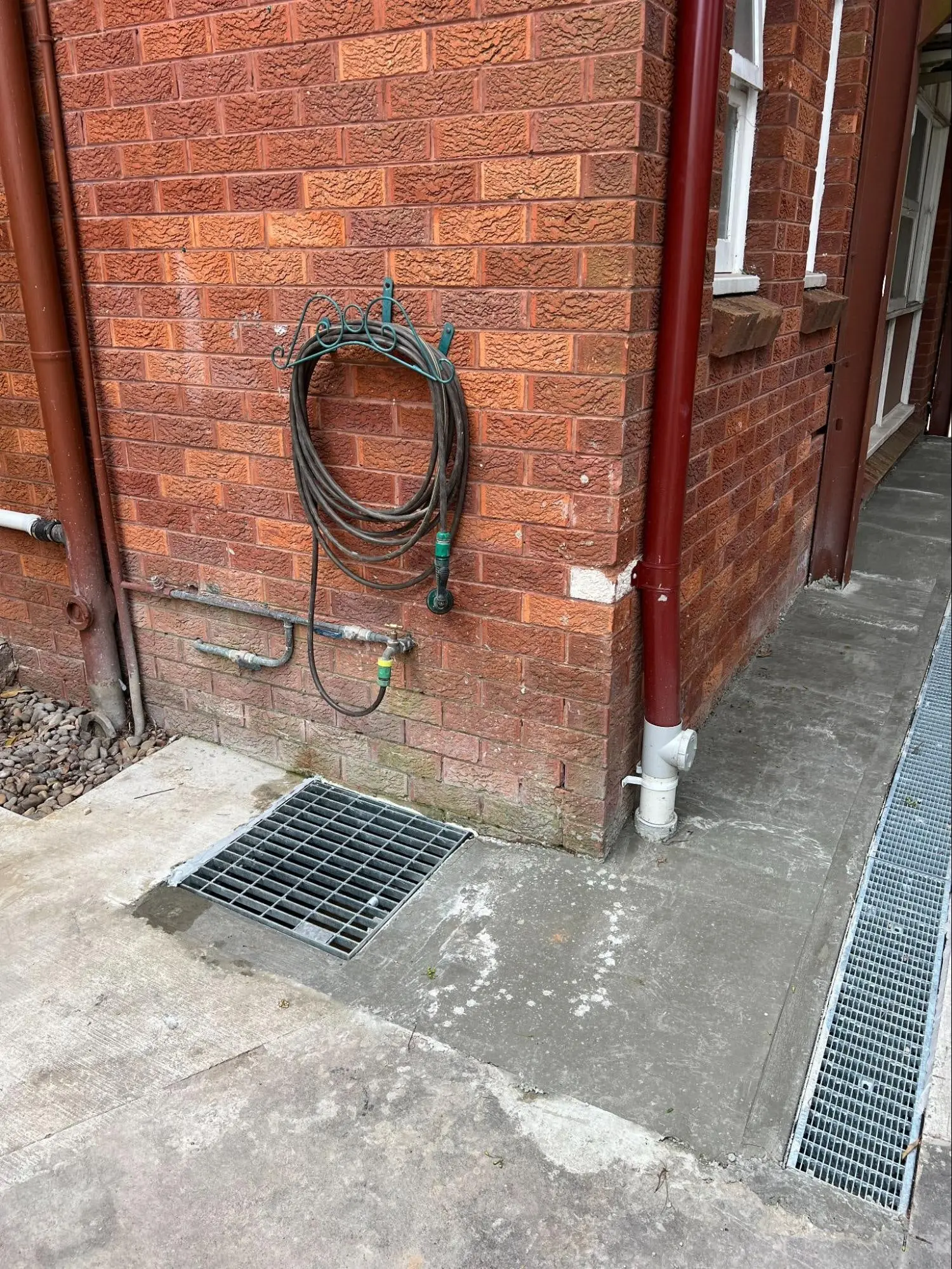 New strip drain and stormwater grate beside a brick house