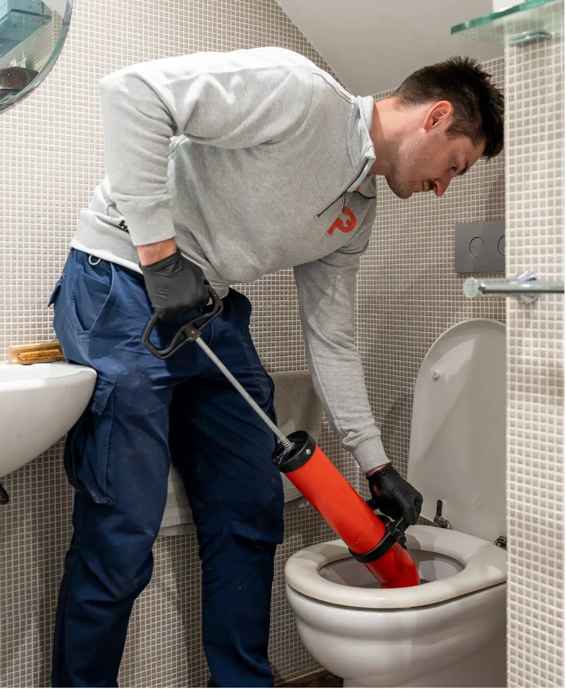Plumber clearing a blocked toilet with a toilet pump