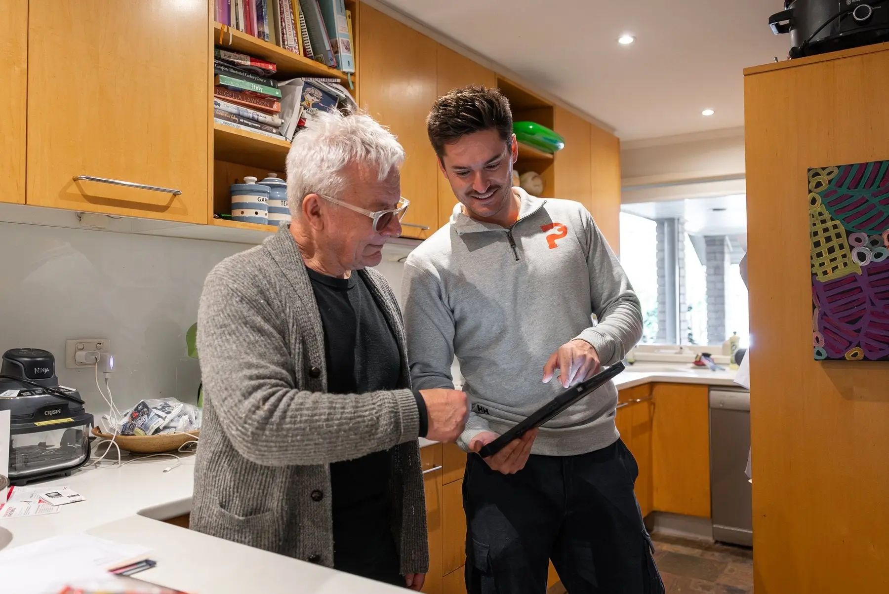 Plumber going through a written quote with a customer in the kitchen