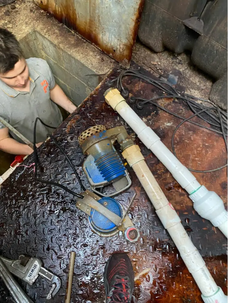 Plumber working on a pump in a drainage pit