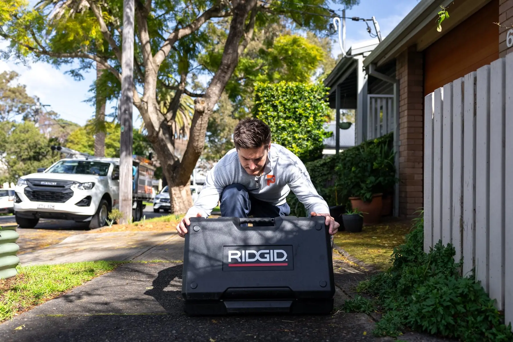 Plumber opening a drain equipment case on a front driveway