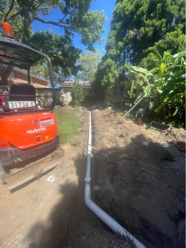 Stormwater pipe laid in a backyard trench beside a mini excavator