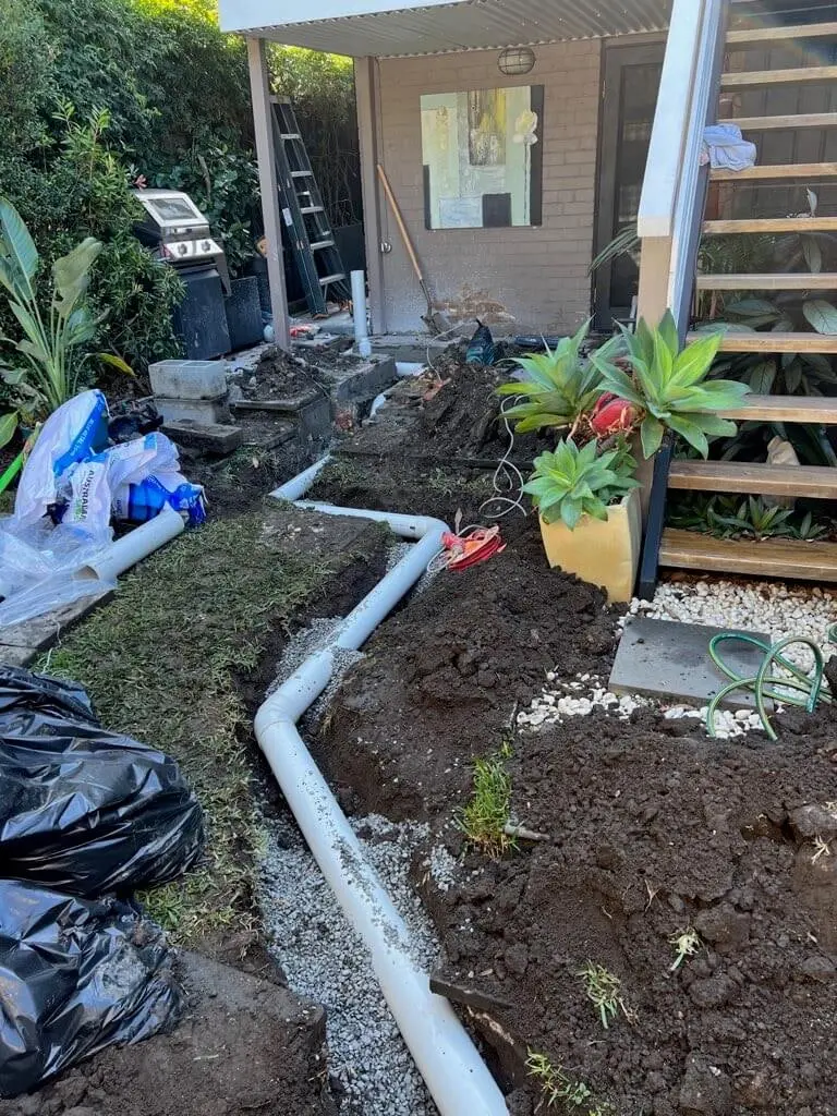 Stormwater pipe trench running through a backyard garden